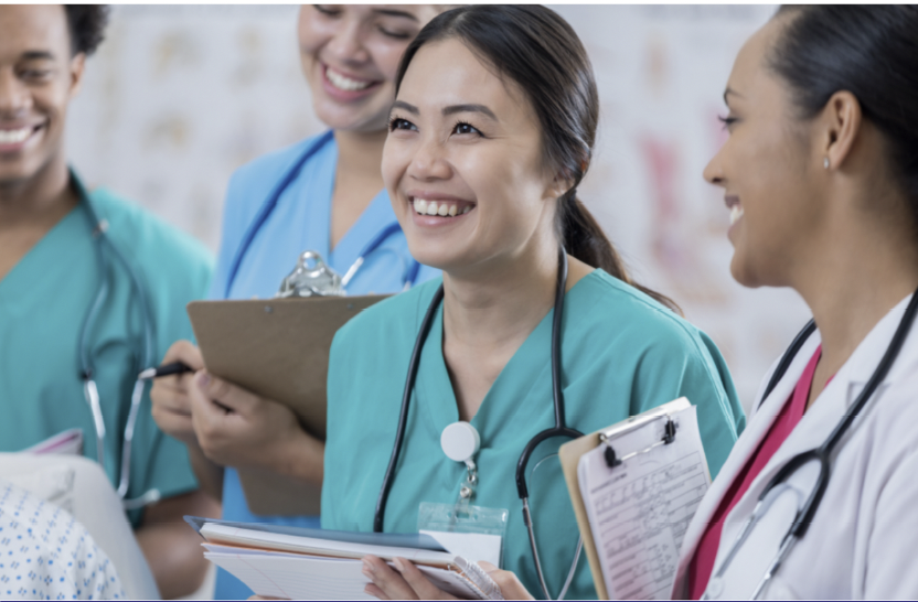 Four medical professionals smiling and holding clipboards