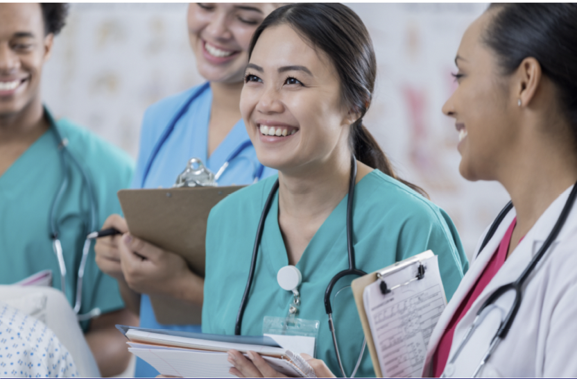 four medical professionals smiling and holding clipboards