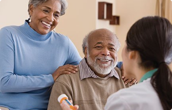 An elderly couple smiling at a medical professional holding a prescription bottle